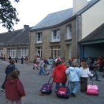 Cour de l'école primaire Léopold DELISLE avec des enfants et leurs cartables.